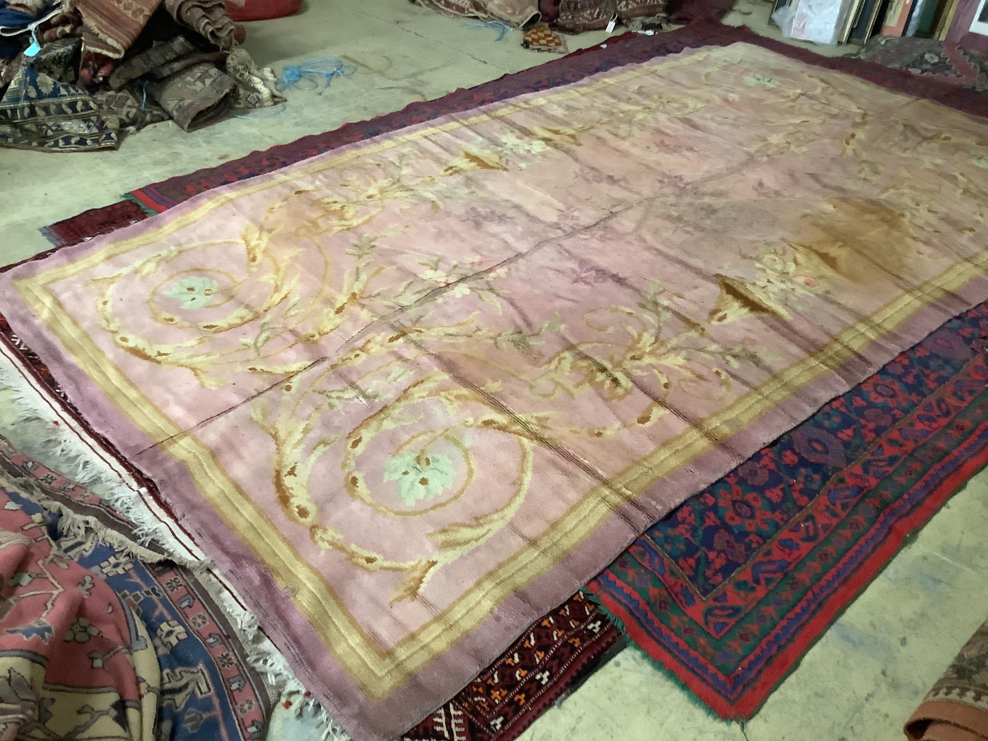 An antique Donegal carpet, with scrolling motifs on a pale, pink ground, cut and reduced in size, 386 x 210cm